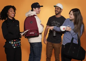 Group with branded backpacks and mugs on orange background