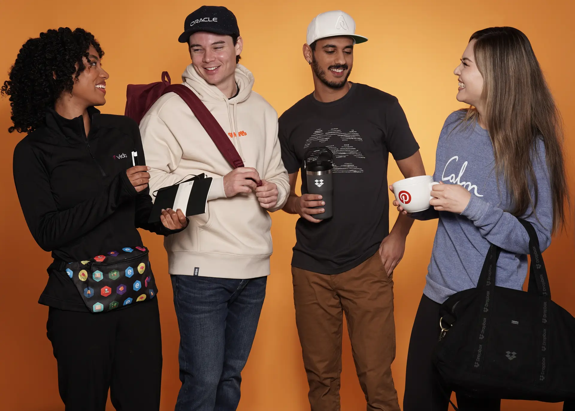 Group showcasing branded apparel and accessories on orange background