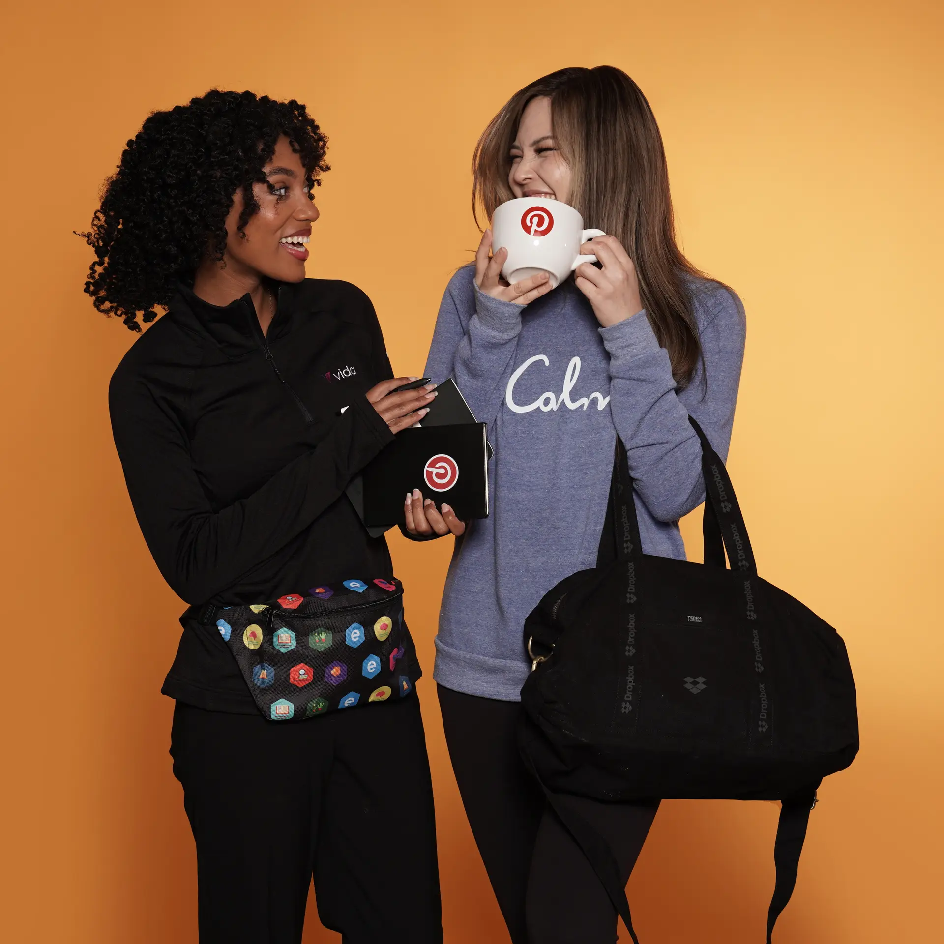 Women holding branded mugs and bags, smiling