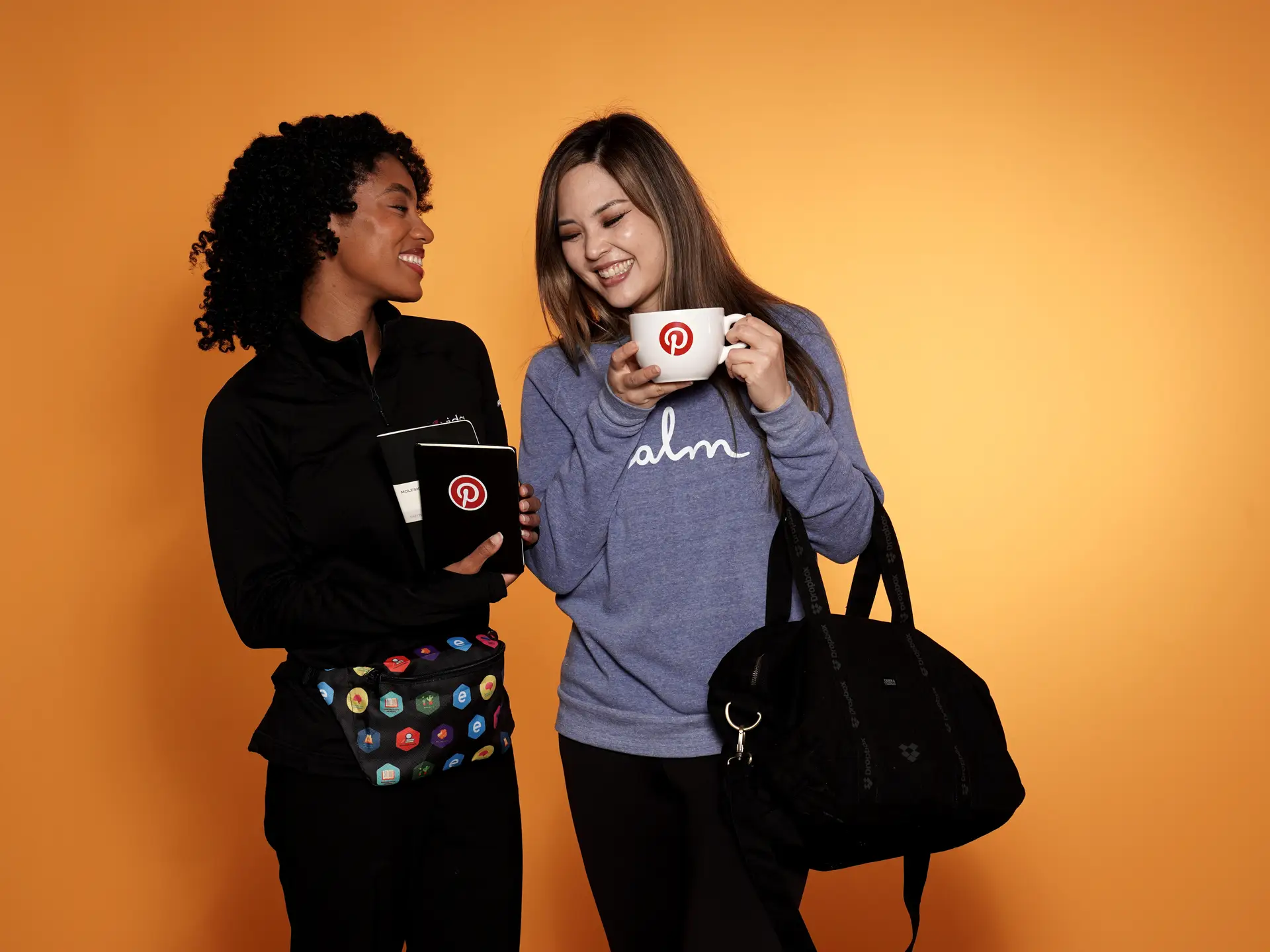 Two women with branded mugs and notebooks