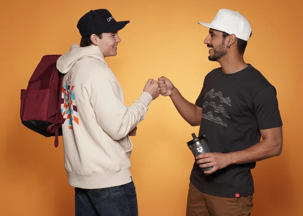 Two men fist bumping, wearing branded apparel