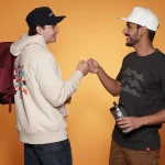 Two men fist bumping, wearing branded apparel