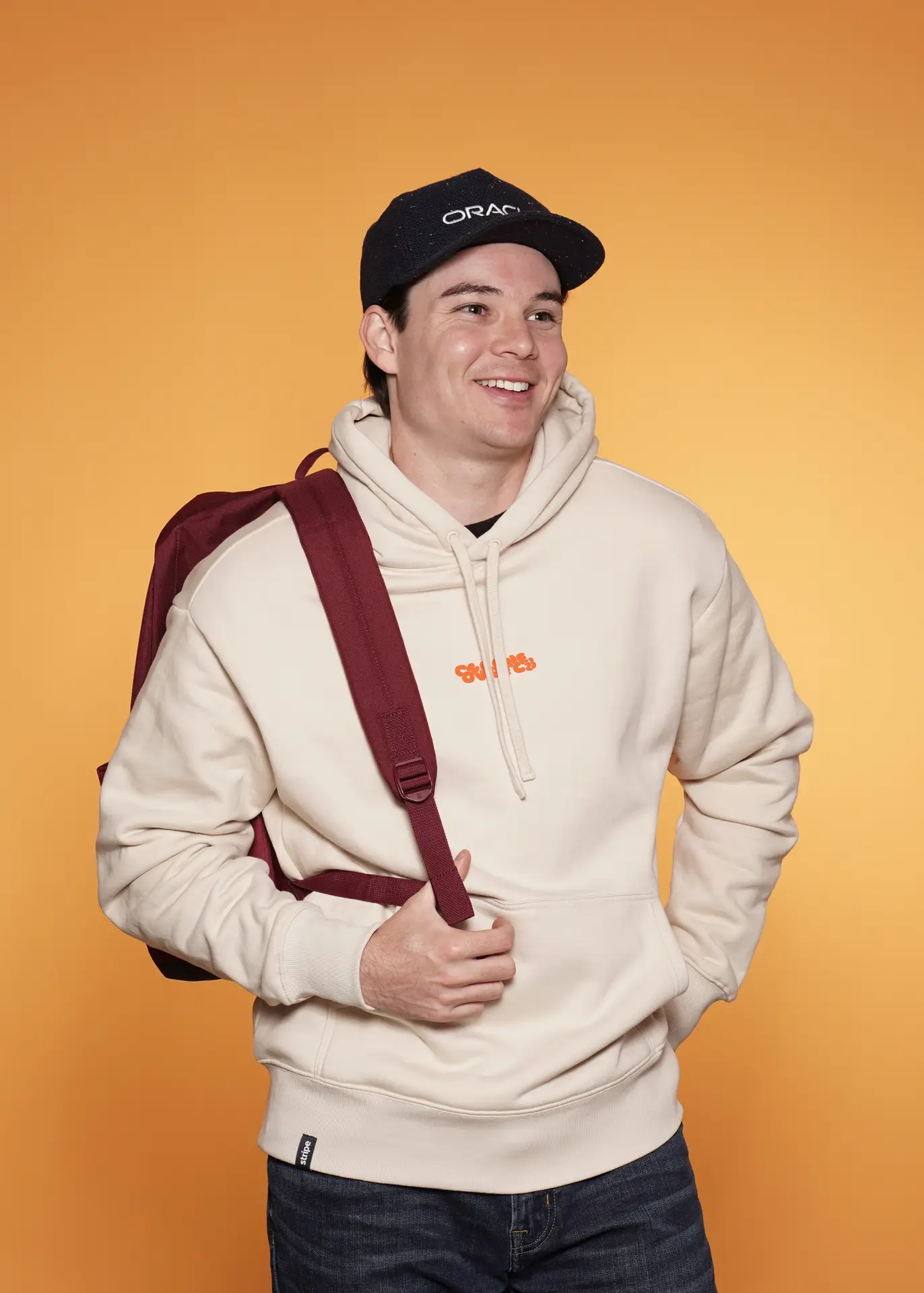 Smiling man in Oracle cap and hoodie with backpack