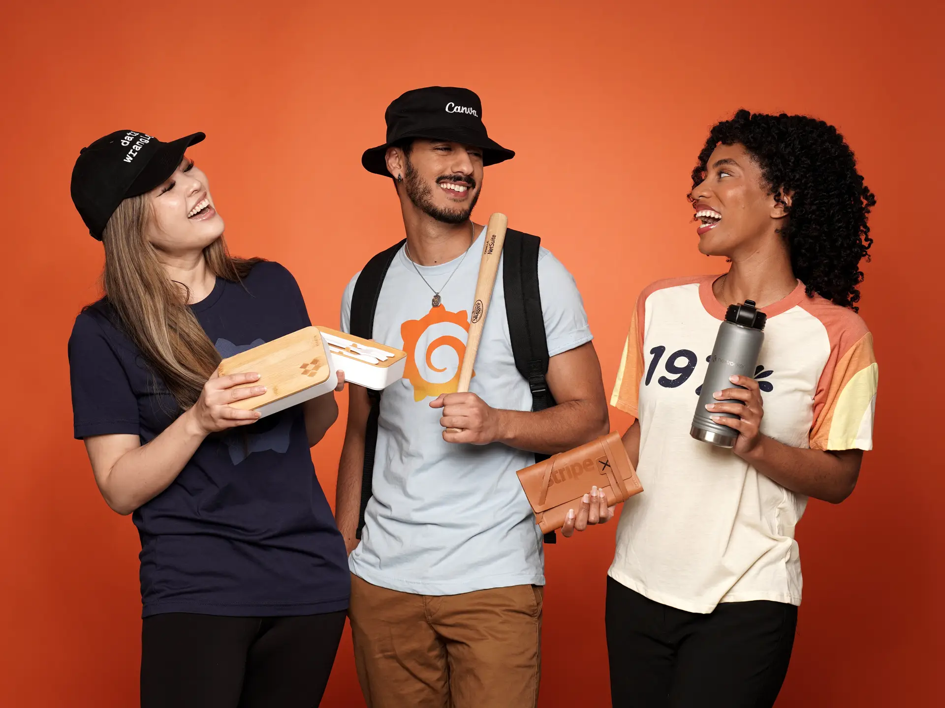 Three people showcasing branded merchandise and smiling