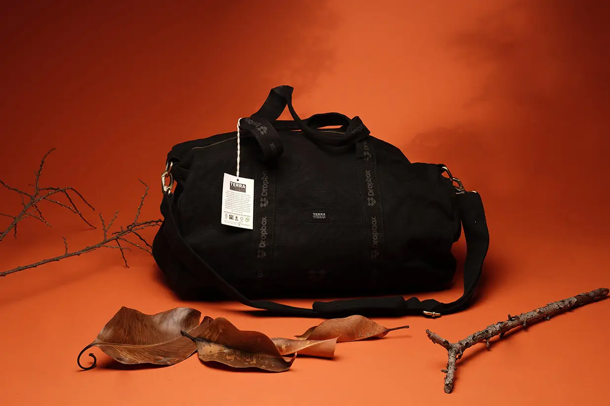Durable black duffel bag with tag, orange backdrop
