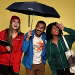 Trio enjoying branded umbrella and tote bag on yellow background