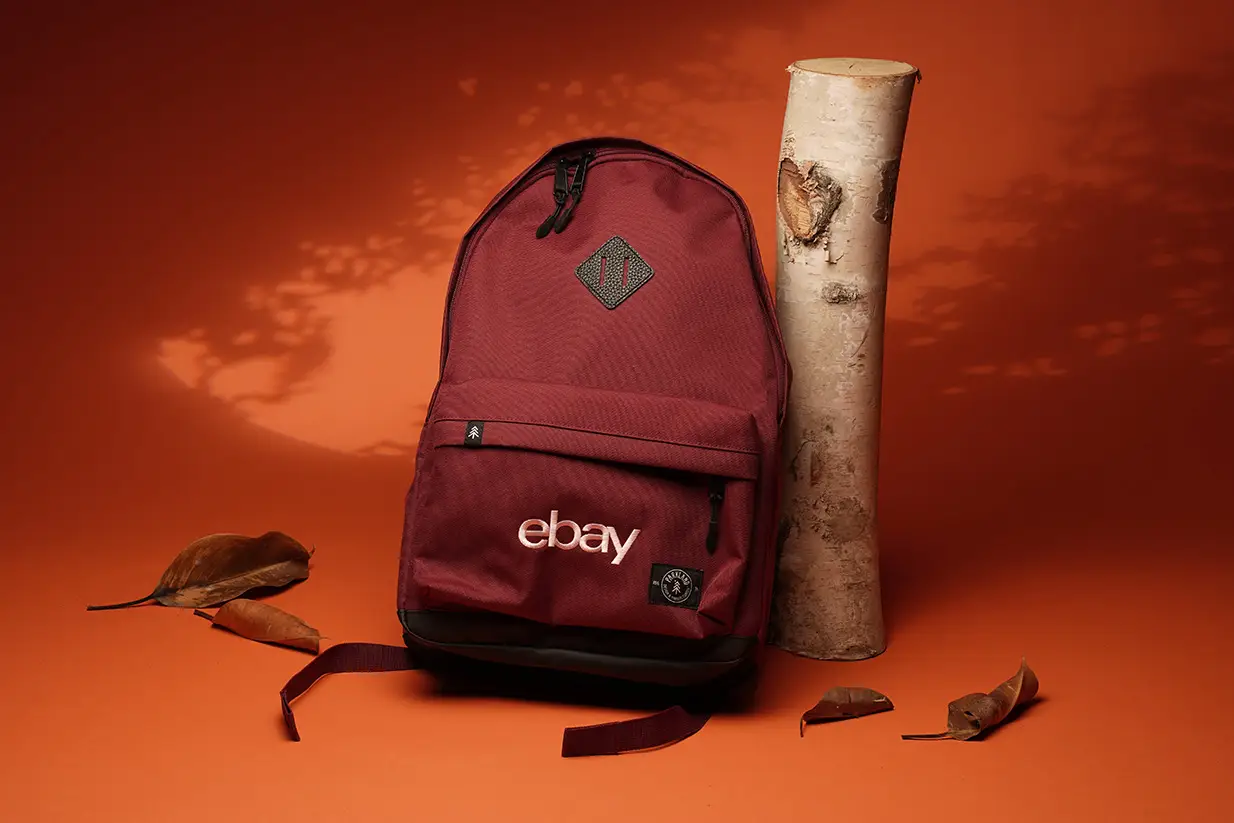 Maroon backpack with logo on orange background