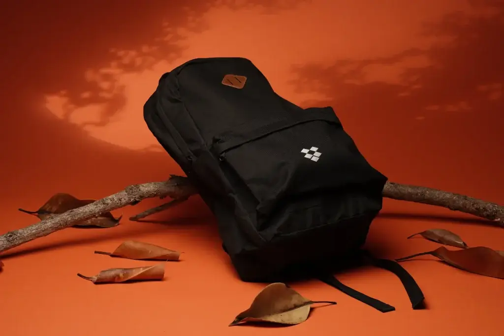 Black backpack with logo on autumn-themed background