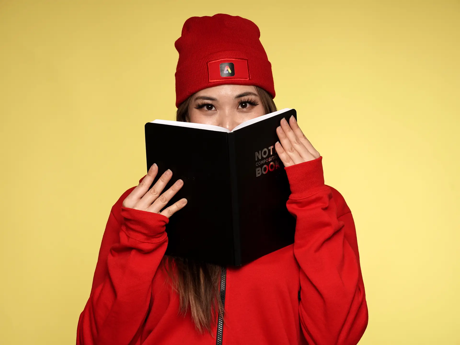 Woman peeking over branded notebook in red outfit