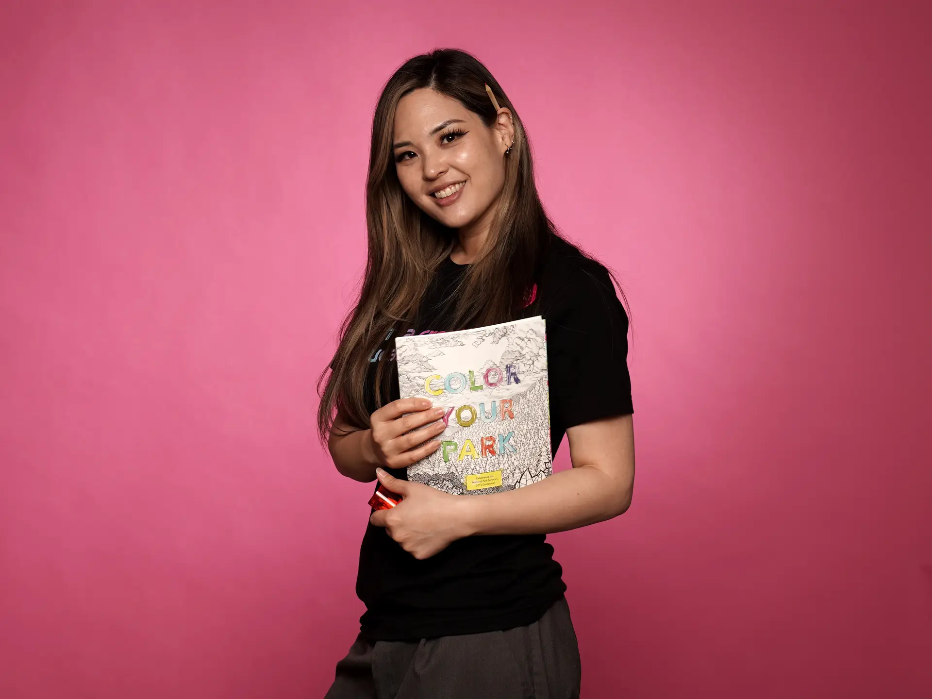 Woman posing with coloring book on pink background