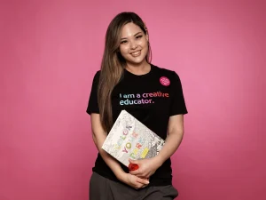 Woman holding a coloring book on pink background
