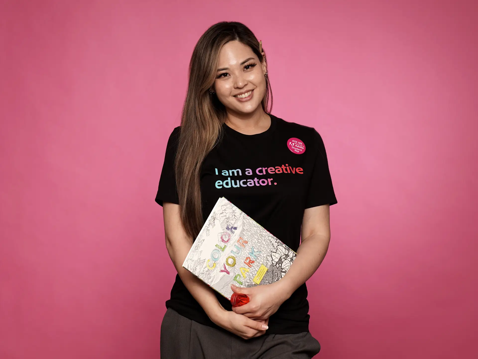 Woman holding a coloring book on pink background