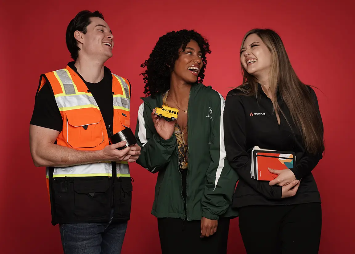 Trio laughing with branded merchandise including notebooks and toys