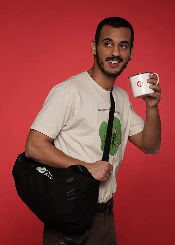 Man posing with branded mug and bag on red background