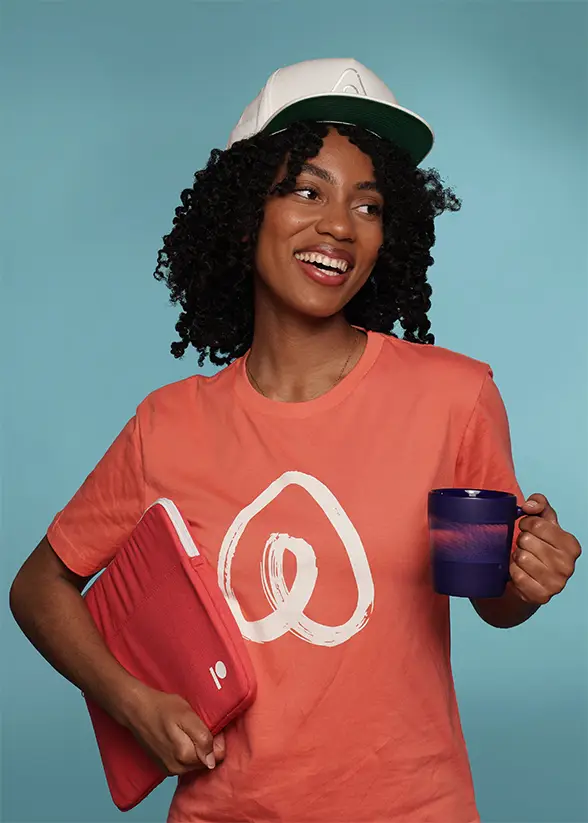 Woman in branded shirt with mug and laptop sleeve