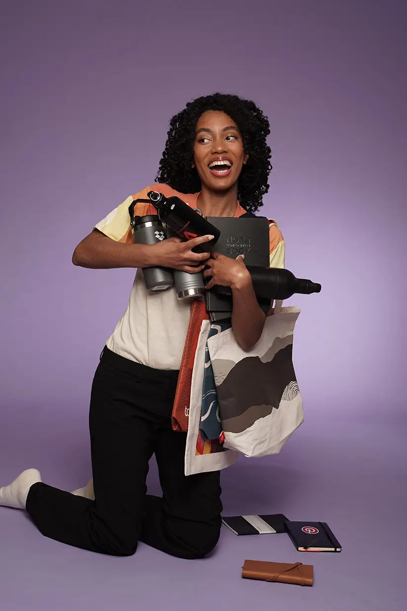 Happy woman holding promotional products and tote bag