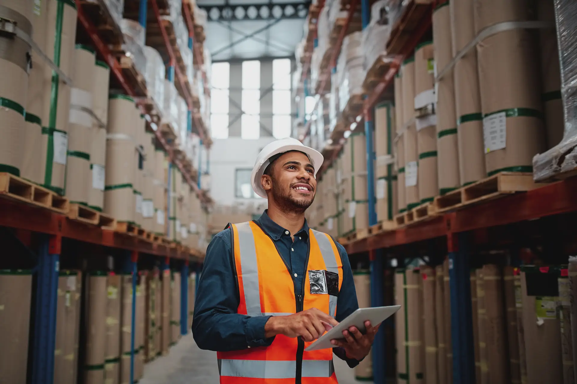 Smiling worker in warehouse with digital tablet
