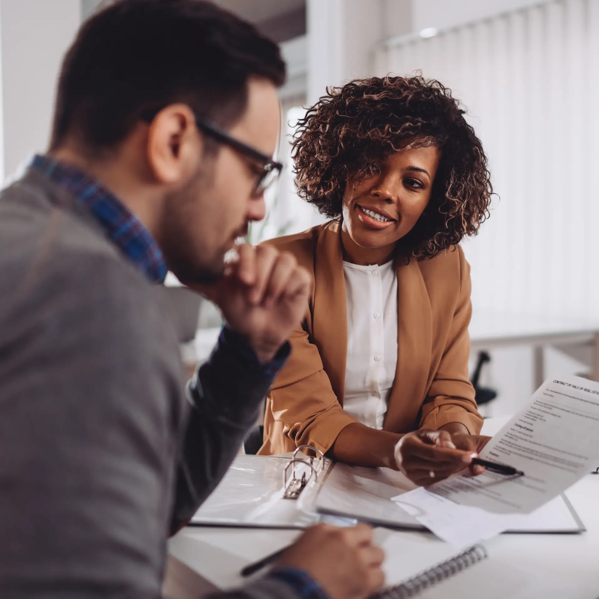 Two professionals discussing contract details in an office setting, illustrating corporate gifting and branded merchandise consultation for employee engagement and event swag solutions.