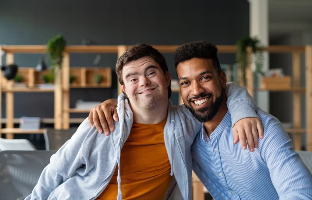Young man with Down syndrome and tutor smiling