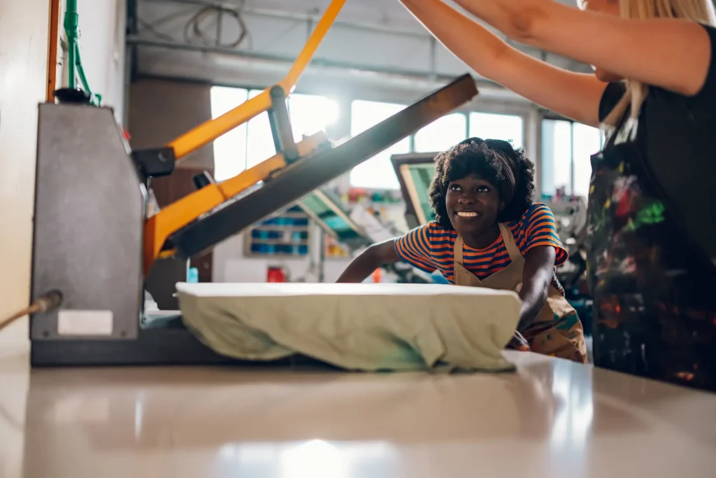 Print shop workers using heat press for custom merchandise