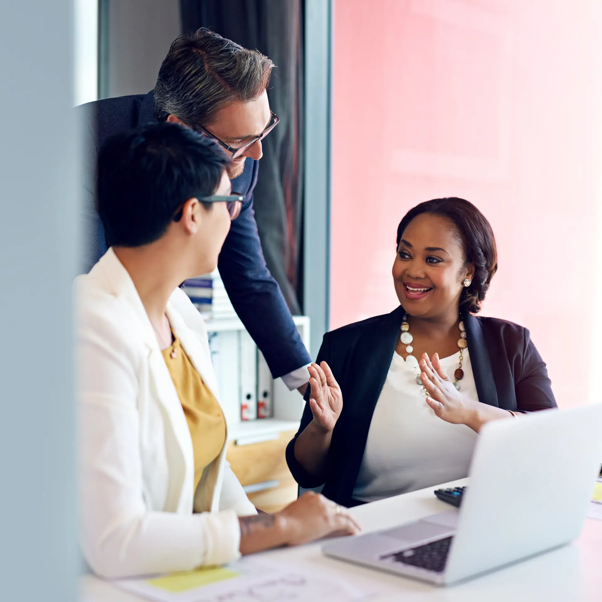 Three diverse business professionals collaborating in an office setting, discussing corporate swag solutions and branded merchandise for employee gifts and event giveaways.