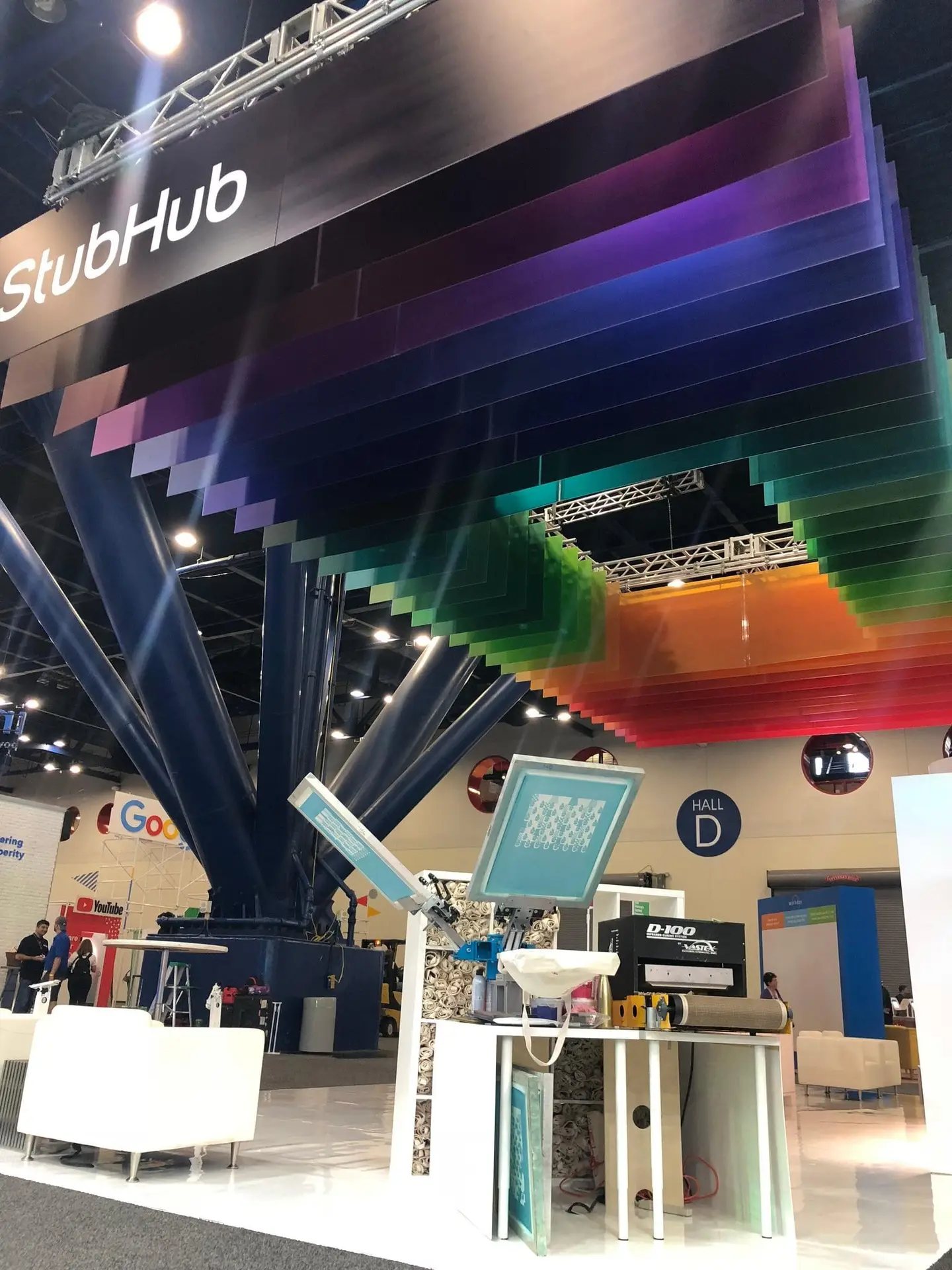 Colorful trade show booth with live screen printing setup and custom branded merchandise for corporate swag and event giveaways.