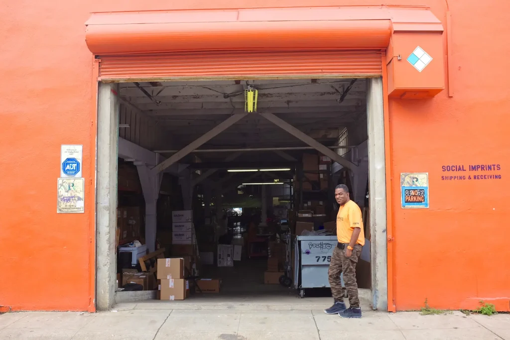 Warehouse entrance of Social Imprints in San Francisco with staff member standing outside, showcasing corporate swag fulfillment and kitting services.