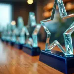 Clear glass star-shaped awards lined up on a wooden table, representing corporate recognition and employee appreciation gifts by a leading promotional products and corporate swag company.