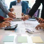 Team collaborating on corporate branding strategy with charts, calculators, and digital devices, showcasing professional planning for custom promotional products, corporate swag, and employee gifting solutions.