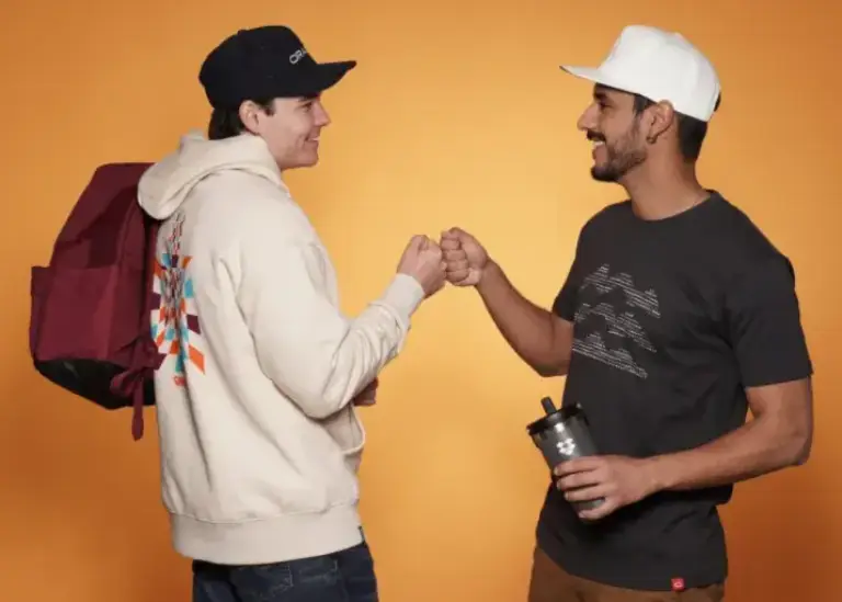Two men fist bump wearing custom branded apparel and accessories, showcasing high-quality corporate swag and promotional products for events and employee gifts.