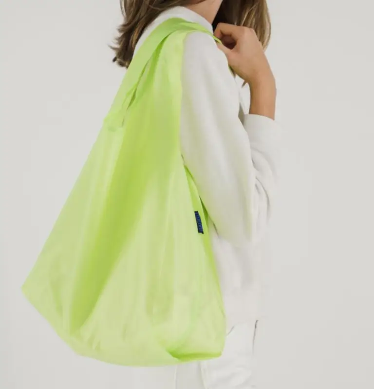 Woman carrying a bright green reusable tote bag, eco-friendly promotional swag item ideal for corporate events and sustainable giveaways.