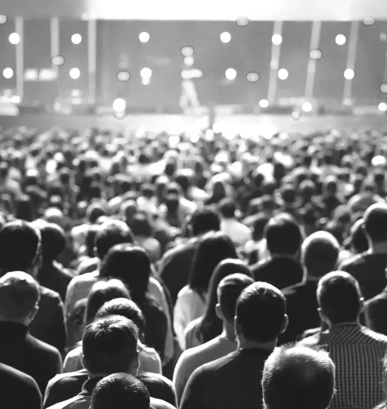 Large crowd attending a corporate event with a speaker on stage, ideal for showcasing swag items for events and promotional products from top corporate swag vendors.