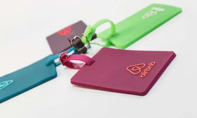 Custom branded silicone luggage tags in vibrant colors with embossed Airbnb logo, showcasing eco-friendly promotional products for corporate gifting and sustainable swag ideas.