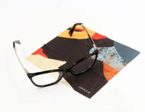 Black rectangular eyeglasses resting on a custom branded colorful microfiber cleaning cloth with Oracle logo, showcasing promotional products for corporate swag and branded merchandise.