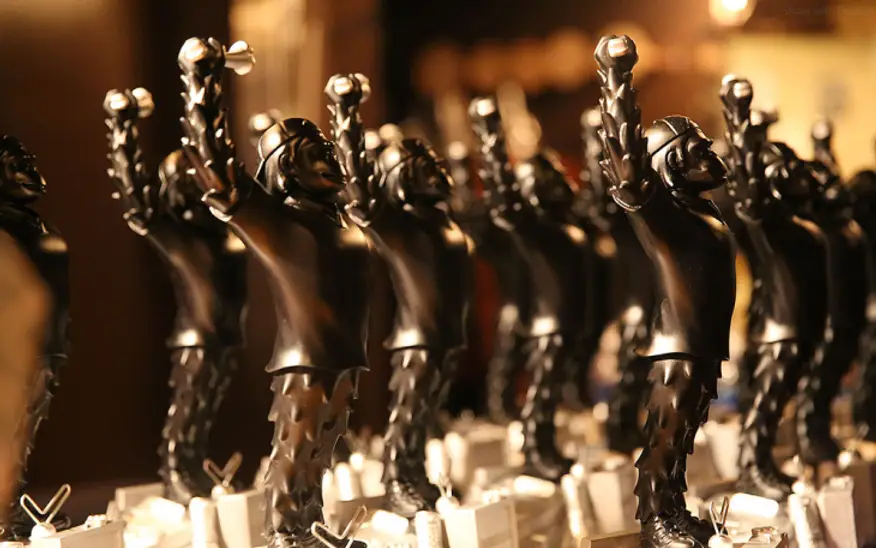 Close-up of custom black event trophies with raised arms, showcasing personalized corporate awards for employee recognition and branded promotional gifts.