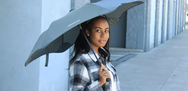 Woman holding custom branded Oracle umbrella outdoors, showcasing promotional products for corporate swag and event giveaways by a top swag company in San Francisco.