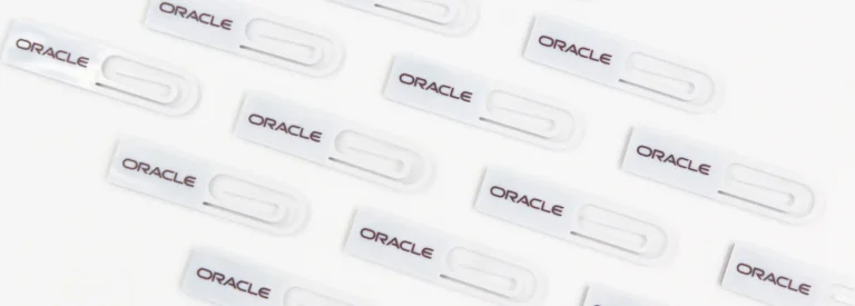 Custom branded white plastic paper clips with Oracle logo, promotional giveaway items for corporate events and trade shows.